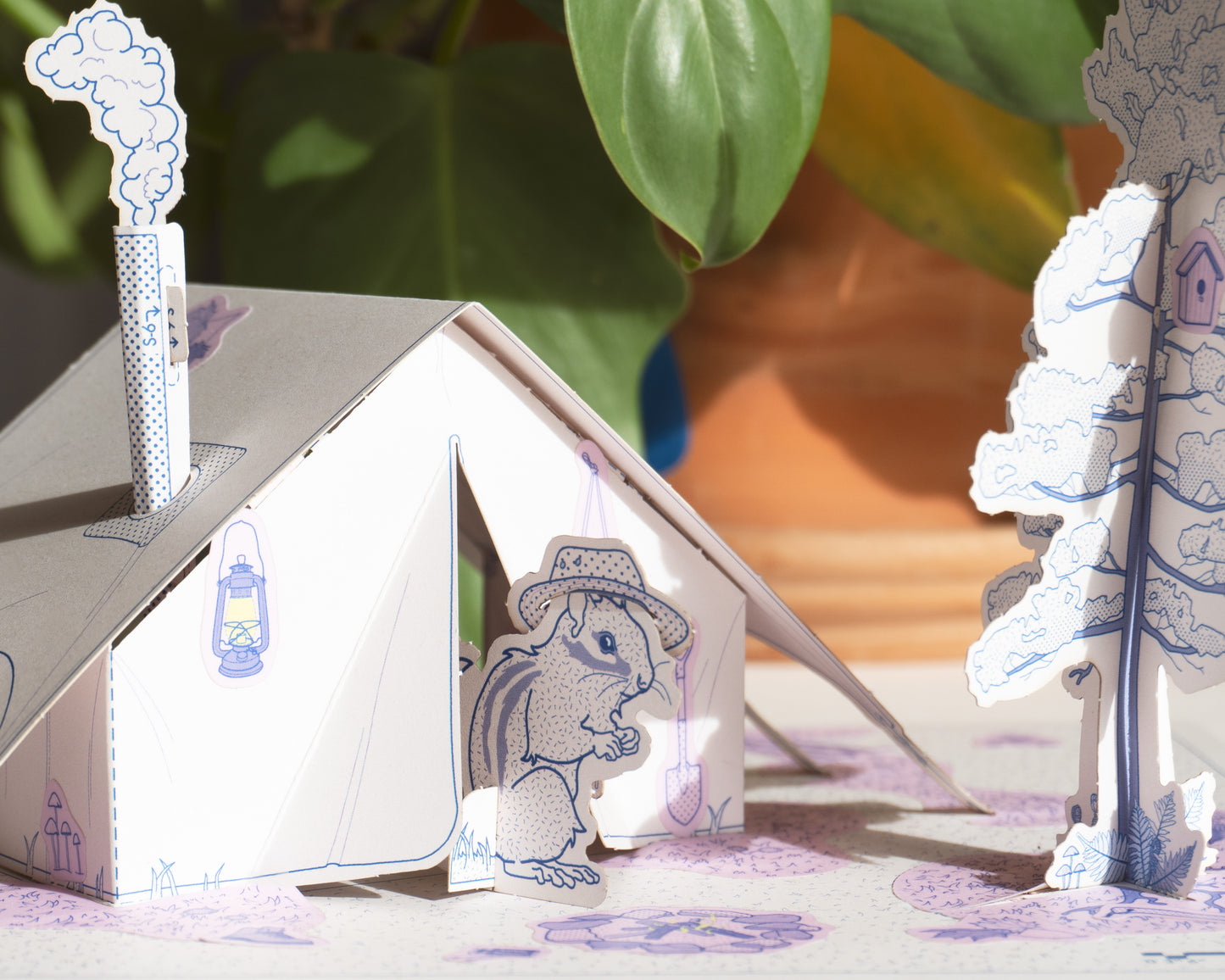A cute adventurous chipmunk peeks out of warm cozy tent playset. Create your own open ended play scenes with Thiskind paper playset kit. 